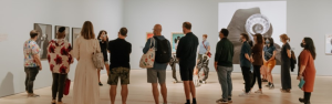 A large group of people view art on the walls of the Polygon Gallery.