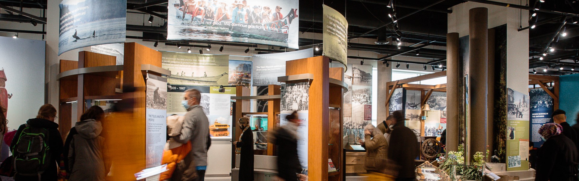 Photo of visitors to the museum of north vancouver looking at Coast Salish images and artifacts.